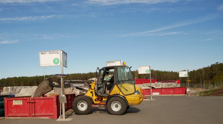 Hjullastare som packar wellpapp i en container på återvinningscentralen